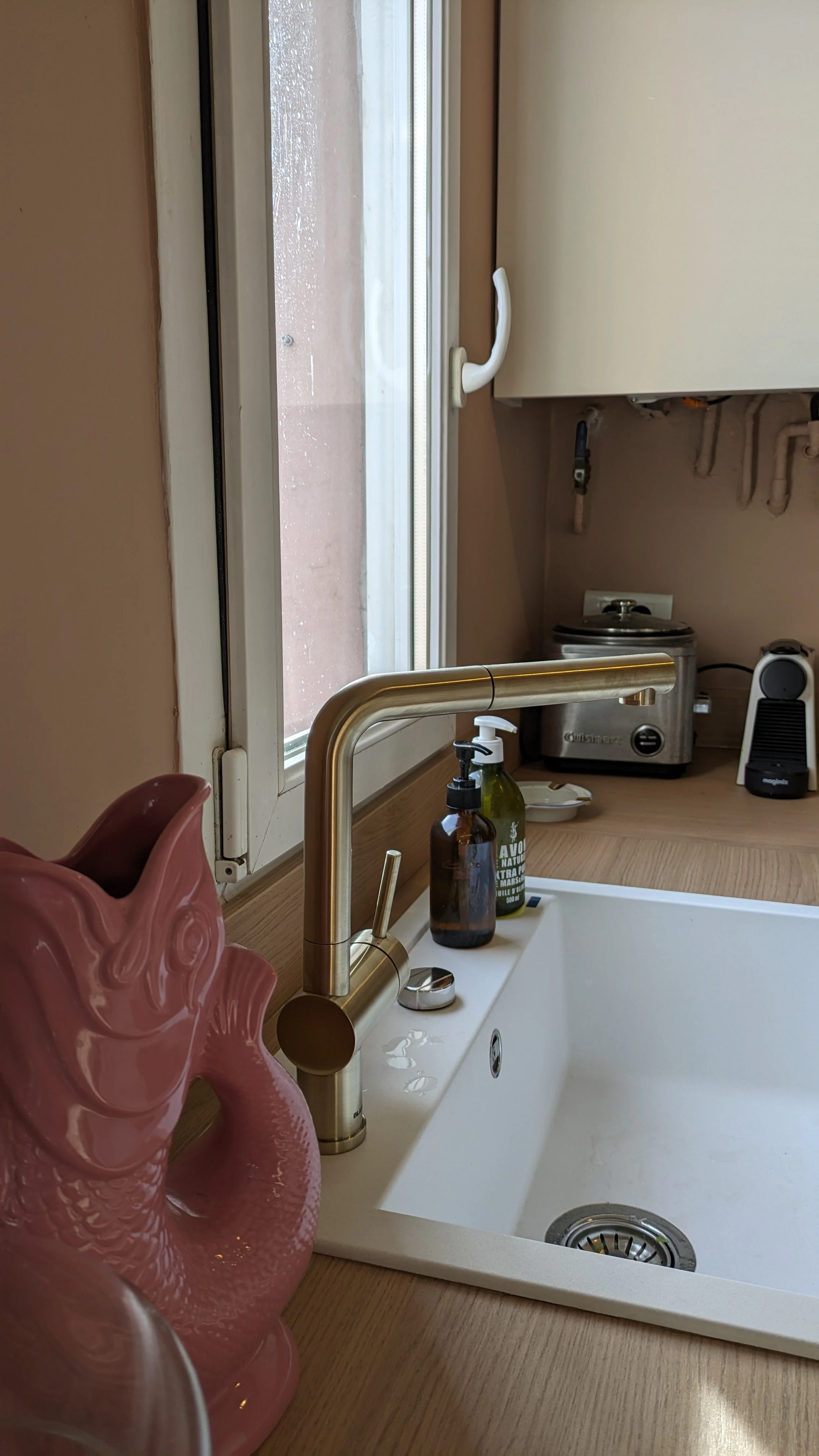 Vue détaillée de la cuisine rénovée avec du terrazzo, des façades blanc cassé, et des touches de rose nude. Un projet sur-mesure d’aménagement intérieur. Cuisine sur-mesure avec evier, silgranit, granit, reconstitué, blanc, blanco, rénovation contemporaine