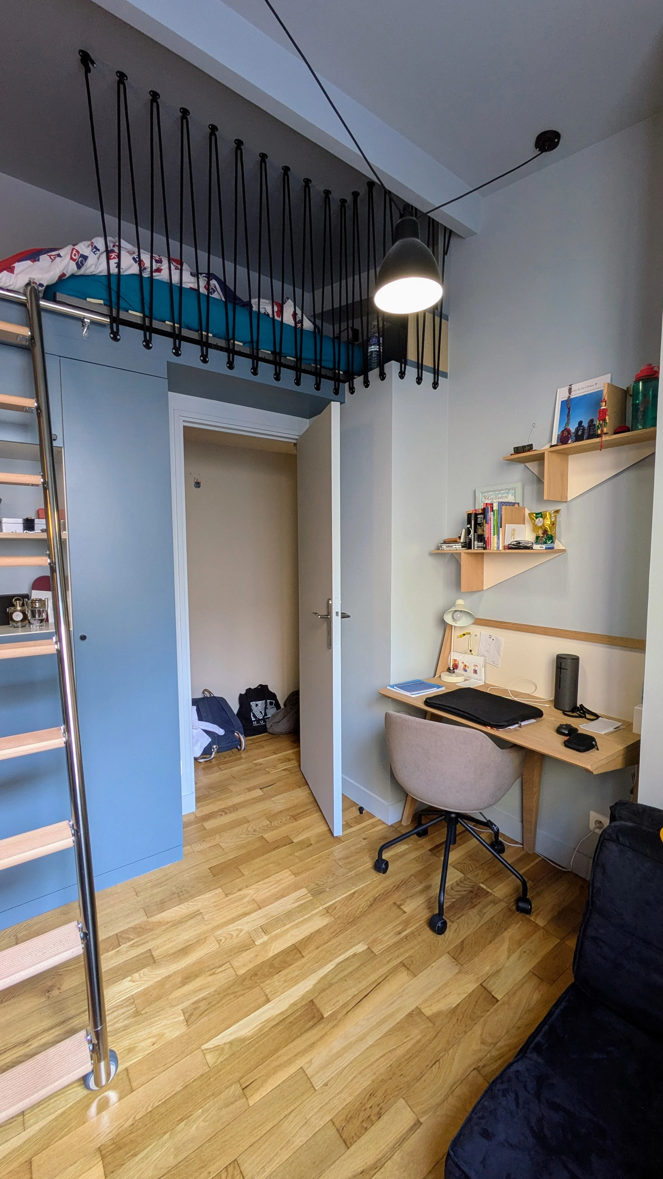 Aménagement astucieux sous les combles avec une mezzanine suspendue, un garde-corps en corde noire graphique et du mobilier sur-mesure pour optimiser l’espace. Chambre sous toiture avec mezzanine sur-mesure, garde-corps en corde noire et mobilier intégré