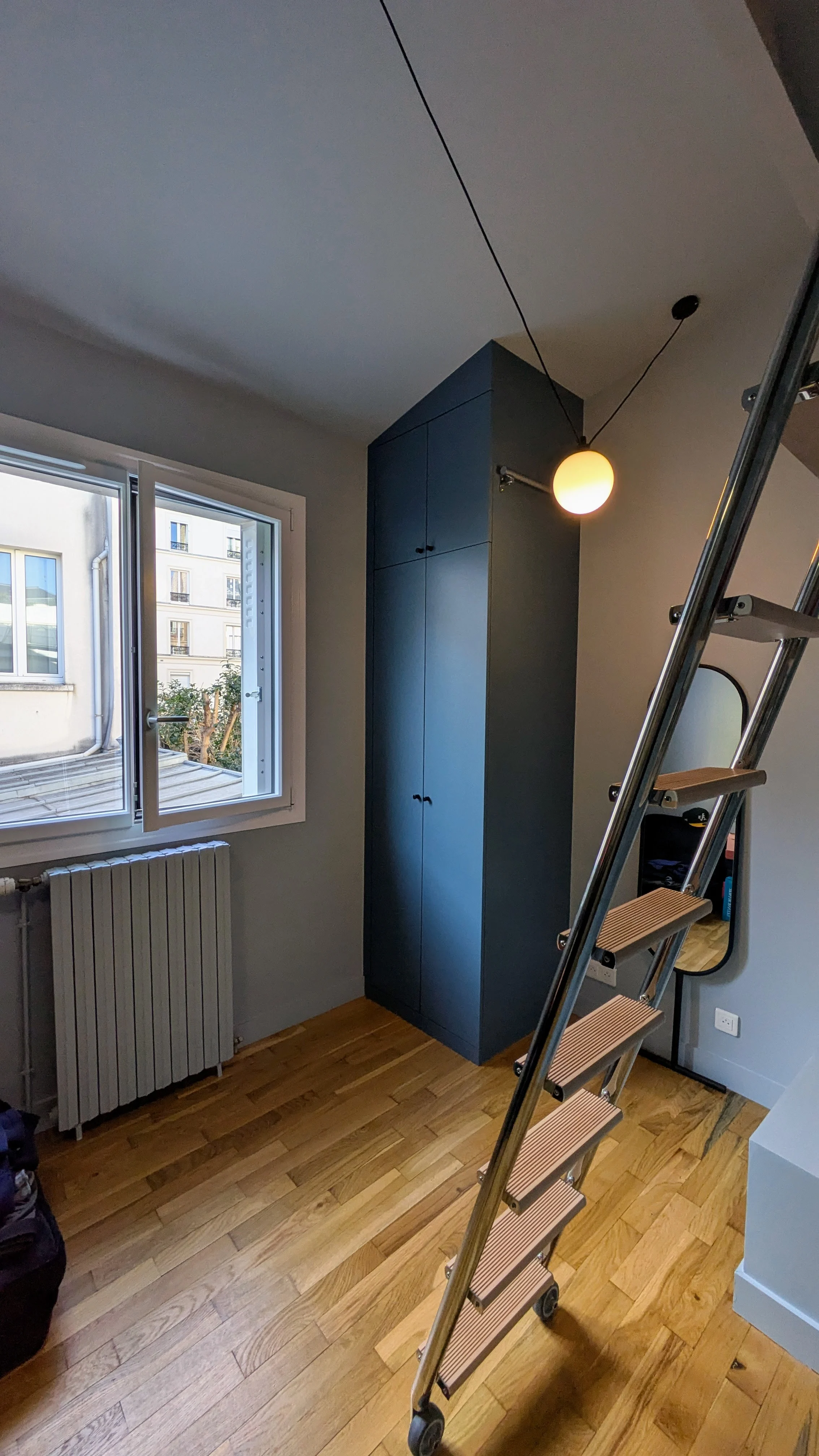 Zoom sur un placard sur-mesure parfaitement intégré aux sous-pentes, peint dans une teinte bleue élégante signée Little Greene. Placard intégré sous pente peint en bleu foncé Little Greene, aménagement sur-mesure