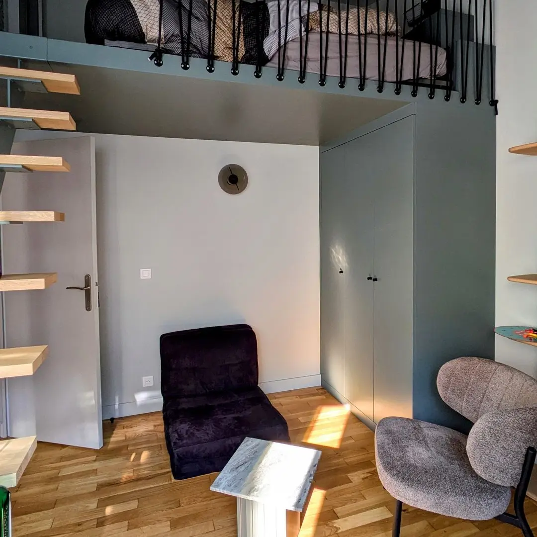 Chambre moderne avec lit mezzanine, escalier en bois, fauteuils design et rangements intégrés