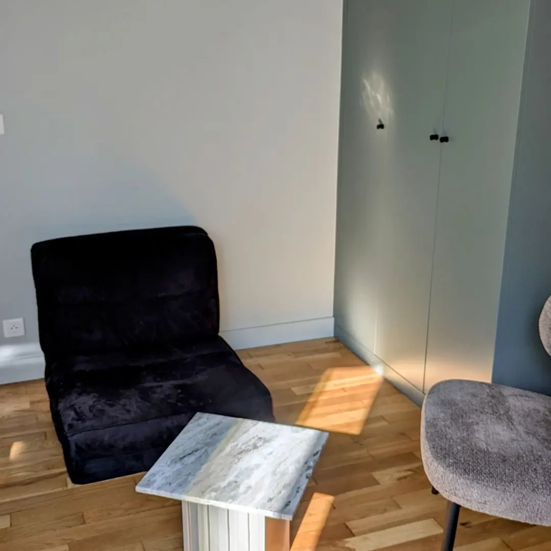 Coin salon de chambre avec fauteuil noir, table basse marbre et placard intégré vert-gris