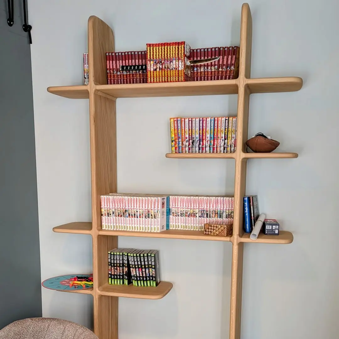 Bibliothèque en bois clair au design contemporain avec étagères décalées et collection de mangas