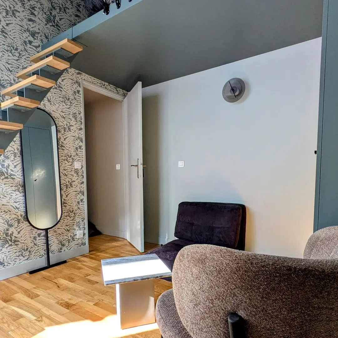 Chambre design avec lit mezzanine, escalier bois, coin salon et papier peint végétal